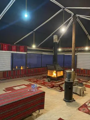 a large tent with a fireplace in the middle of a patio at Milky Way Wadi Rum in Wadi Rum