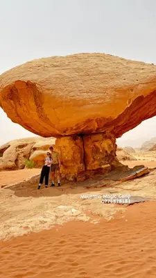 two people standing under a rock in the desert at Princess Camp in Wadi Rum