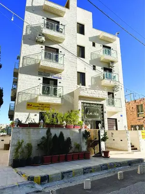 a white building with balconies and plants in front of it at Alsadi Housing- Jabal Amman in Amman
