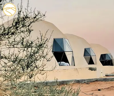 a dome shaped building in the desert with windows at Amber Luxury Camp in Maḩaţţat Dīsah