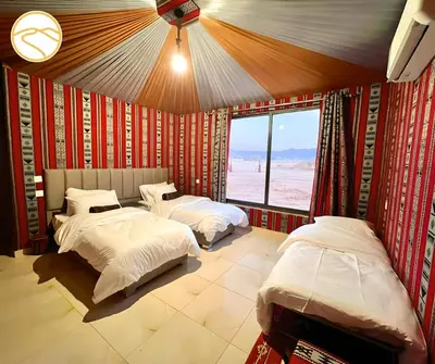 two beds in a room with a view of the desert at Amber Luxury Camp in Maḩaţţat Dīsah