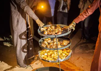 a group of people holding three trays of food at Desert Waves Camp in Wadi Rum