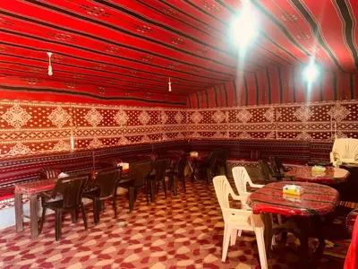 a restaurant with red walls and tables and chairs at Panorama Wadi Rum Sunset Camp in Wadi Rum