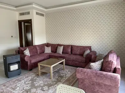 a living room with a purple couch and a table at 7th Circle Apartment in Amman