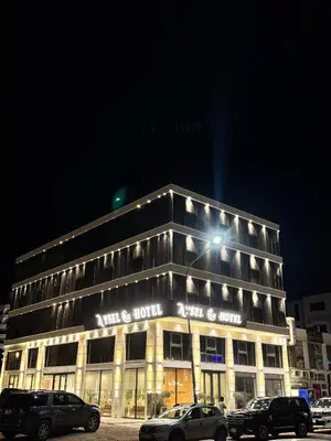 a lit up building with cars parked in front of it at Aysel Hotel in Aqaba