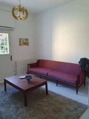 a red couch in a living room with a table at One-of-Kind home - city & nature in Amman