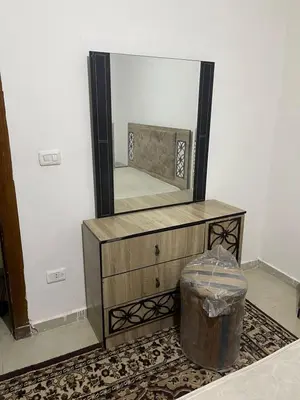a mirror on top of a wooden dresser with a trash can at Ara Home in Amman
