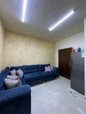 a living room with a blue couch and a refrigerator at Osama Alnaser in Amman