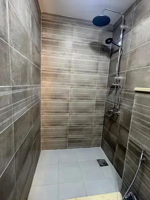 a bathroom with a shower with a tiled wall at Qastal Zaman in Amman