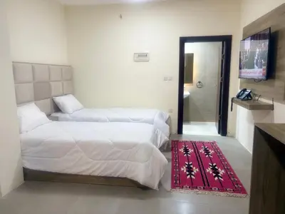 a bedroom with two beds and a red rug at Qastal Zaman in Amman