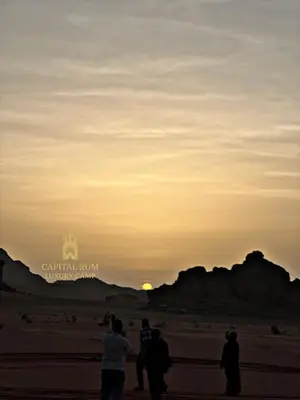 a group of people standing on a beach flying a kite at CAPITAL RUM lUXURY CAMP in Wadi Rum