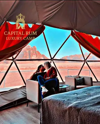 two people sitting in a tent looking out at the desert at CAPITAL RUM lUXURY CAMP in Wadi Rum