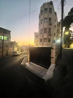 a building on the side of a street with a fence at Modern, fully equipped apartment in Jabal Amman in Amman
