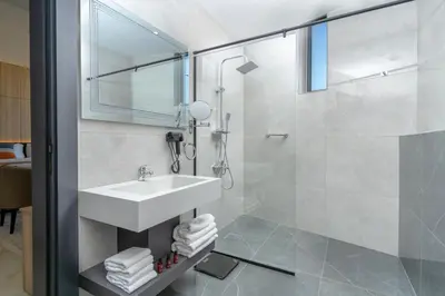 a white bathroom with a sink and a shower at Diamond Palm Hotel & Resort in Al Burj