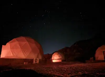 two domes in the desert lit up at night at Olivia Rum Luxury Bubbles & Jeep Tours in Wadi Rum