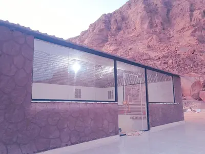 a building with a mountain in the background at Olivia Rum Luxury Bubbles & Jeep Tours in Wadi Rum