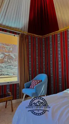 a room with a bed and a chair in a tent at Grand Bubble rum luxury in Wadi Rum