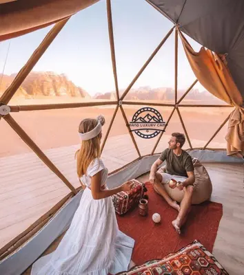 a woman and a man sitting in a tent at Grand Bubble rum luxury in Wadi Rum