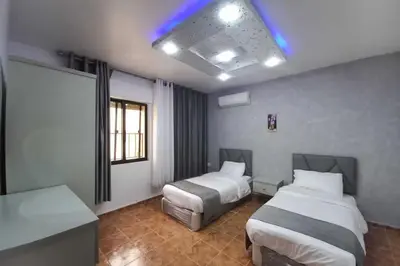 a hotel room with two beds and a window at Al-Nujoom Hotel Suites in Amman