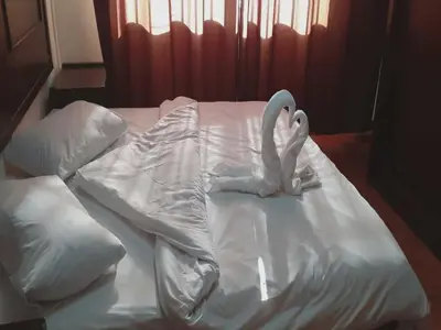 a white bed with two swans made out of pillows at Al-Nujoom Hotel Suites in Amman