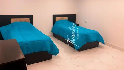 two beds with blue covers in a room at CityHaven in Amman