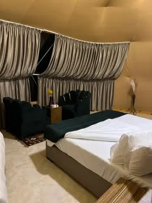 a bedroom with a bed with curtains and a couch at HOlIDAY LUXURY WADI RUM in Wadi Rum