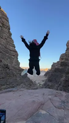 a person jumping in the air over some rocks at Alkaram luxury camp in Wadi Rum
