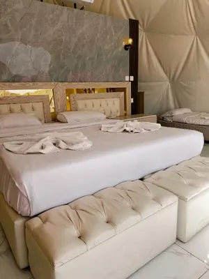 a large white bed with a couch in a room at The Flowers Camp in Wadi Rum