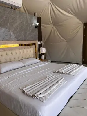 a bed with white sheets and towels on it at The Flowers Camp in Wadi Rum