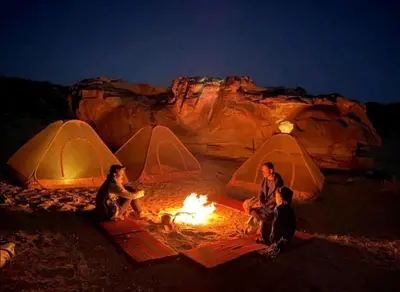 a group of people sitting around a fire in front of tents at مخيم وهج رم in Disah