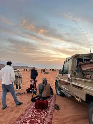 a group of people standing around a truck in the desert at Rum drone tours in Aqaba