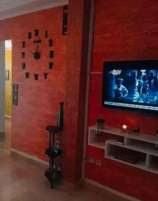 a living room with a wall with a tv and a clock at Loard House in Az Zarqa