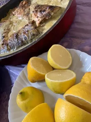 a plate with lemons and a pan of food at Board apartment in Irbid