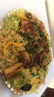 a plate of food with rice and meat and vegetables at Board apartment in Irbid