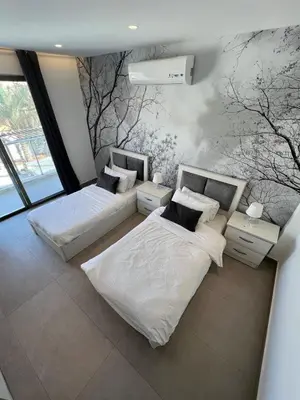 two beds in a room with trees on the wall at Eva chalet in Deadsea in Al Kafrayn