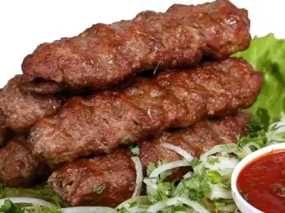 a pile of meatballs on a salad with sauce at Rawabi INN in Maţār al Malik Ḩusayn