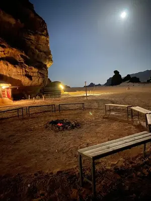a group of benches sitting on a beach at night at Rose Al Ghaith Camp in Disah