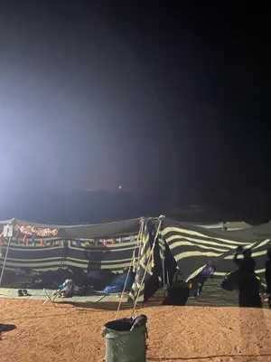 a group of tents on a beach at night at The heartbeat of the desert and the stars in Wadi Rum