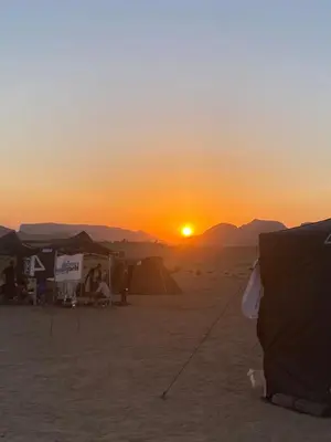a sunset on the beach with tents in the sand at The heartbeat of the desert and the stars in Wadi Rum