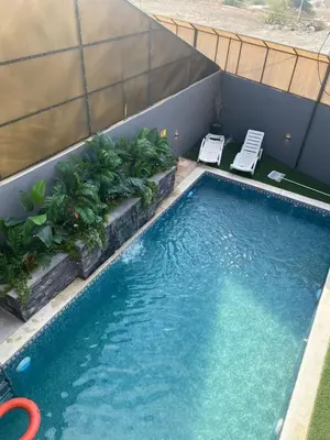 a large swimming pool with two lawn chairs and plants at SAN VITO Chalet in Sowayma