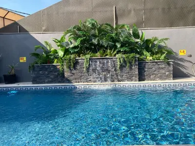 a swimming pool with plants on the side of a building at SAN VITO Chalet in Sowayma
