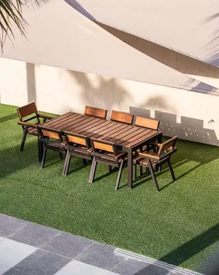 a wooden table and chairs sitting next to a building at Las palmas resort in Sowayma