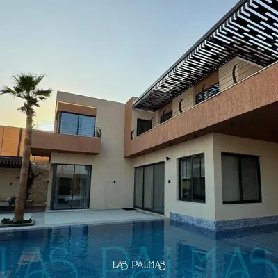 a building with a palm tree next to a swimming pool at Las palmas resort in Sowayma