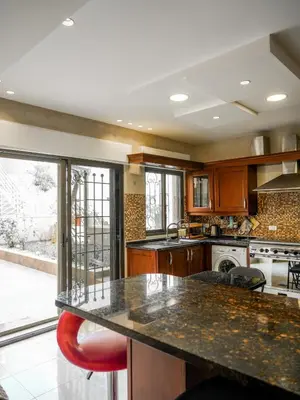 a kitchen with a counter and a large window at Yafa 2BR N Abdoun Apartment in Amman