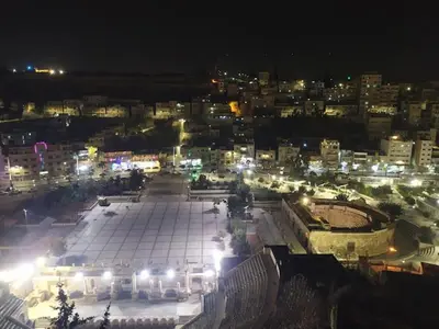 a view of a city at night with lights at over theatre apartment in Amman