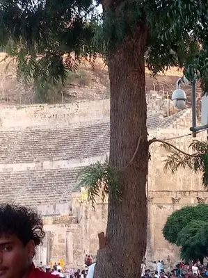 a man is standing next to a tree at over theatre apartment in Amman