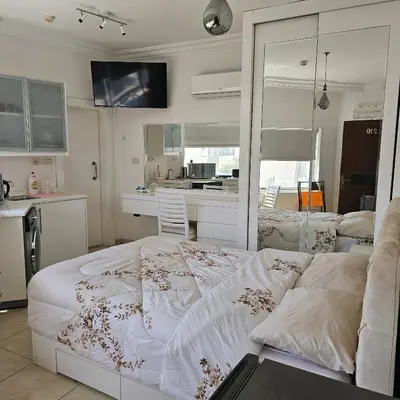a bedroom with a white bed and a kitchen at Cozy apartment in Amman