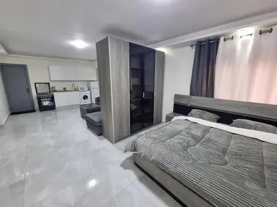 a bedroom with a large bed and a kitchen at Sama Dier Ghbar 1 in Amman