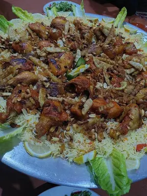 a plate of food with chicken and rice at Nassen House in Udhruḩ