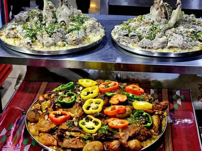 two pizzas with tomatoes on them on a table at Nassen House in Udhruḩ